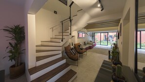 A modern interior with a staircase, seating area, and potted plants. - Casa Tonal (Mexico City)