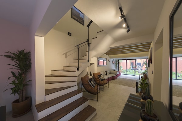 A modern interior with a staircase, seating area, and potted plants. - Casa Tonal (Mexico City)