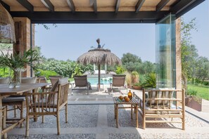 Un área de estar al aire libre con piscina, una sombrilla de paja y vistas del paisaje.