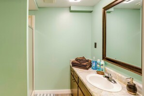 Une salle de bain équipée d’un lavabo, d’un miroir et d’articles de toilette.