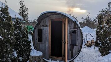 Una cabaña rústica cubierta de nieve, con puerta de madera y un pequeño porche.