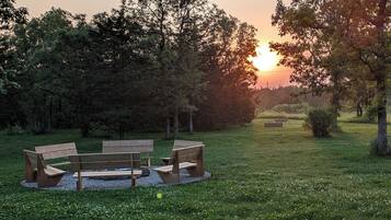 A park with a wooden bench and a circular seating area surrounded by grass and trees.