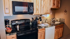 A kitchen with wooden cabinets, a microwave, stove, sink, and dishwasher. - Fawn Valley Inn: 284 1 Bedroom Condo (Estes Park)
