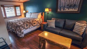 A room with a bed, a sofa, a bench, and a wall-mounted lamp. - Sunnyside Knoll: 2 Cottage (Estes Park)