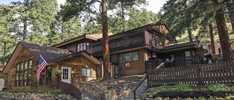 A log cabin with a stone foundation, wooden deck, and a flag.