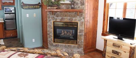 A cozy room with a stone fireplace, a television, and a bed with a quilt.