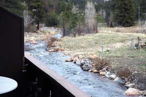 A river flowing through a natural landscape with a wooden deck and a table in the foreground.