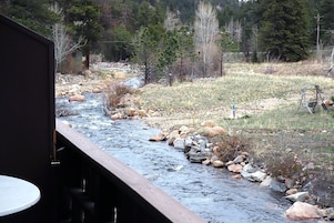 Un fiume che scorre attraverso un paesaggio naturale, con una terrazza in legno e un tavolo in primo piano.