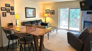 A living room with a dining area, a sofa, two lamps, and a TV. - Fawn Valley Inn: 292 1 Bedroom Apts (Estes Park)