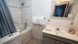 Un baño con inodoro, bañera, lavamanos y espejo.
