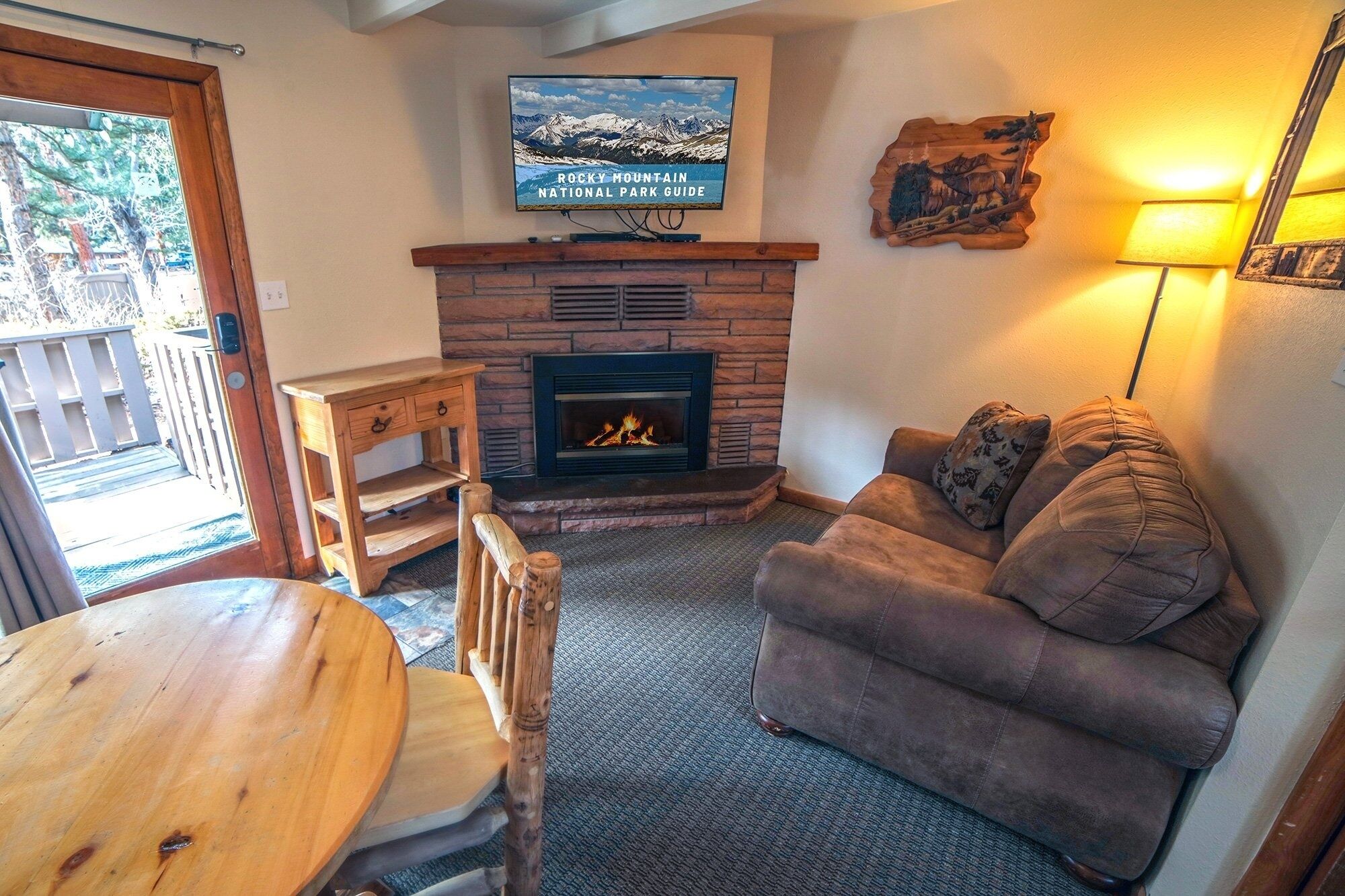 A cozy living room with a fireplace, a television mounted above it, and a comfortable couch.
