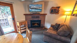 A cozy living room with a fireplace, a television mounted above it, and a comfortable couch. - Sunnyside Knoll: 14 Studio (Estes Park)