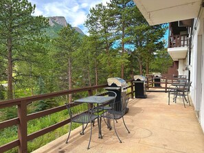 Eine Terrasse im Freien mit Grill, Metallstühlen und Tischen.