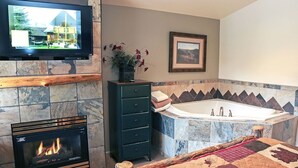 A modern bathroom with a fireplace, a large mirror, and a bathtub.