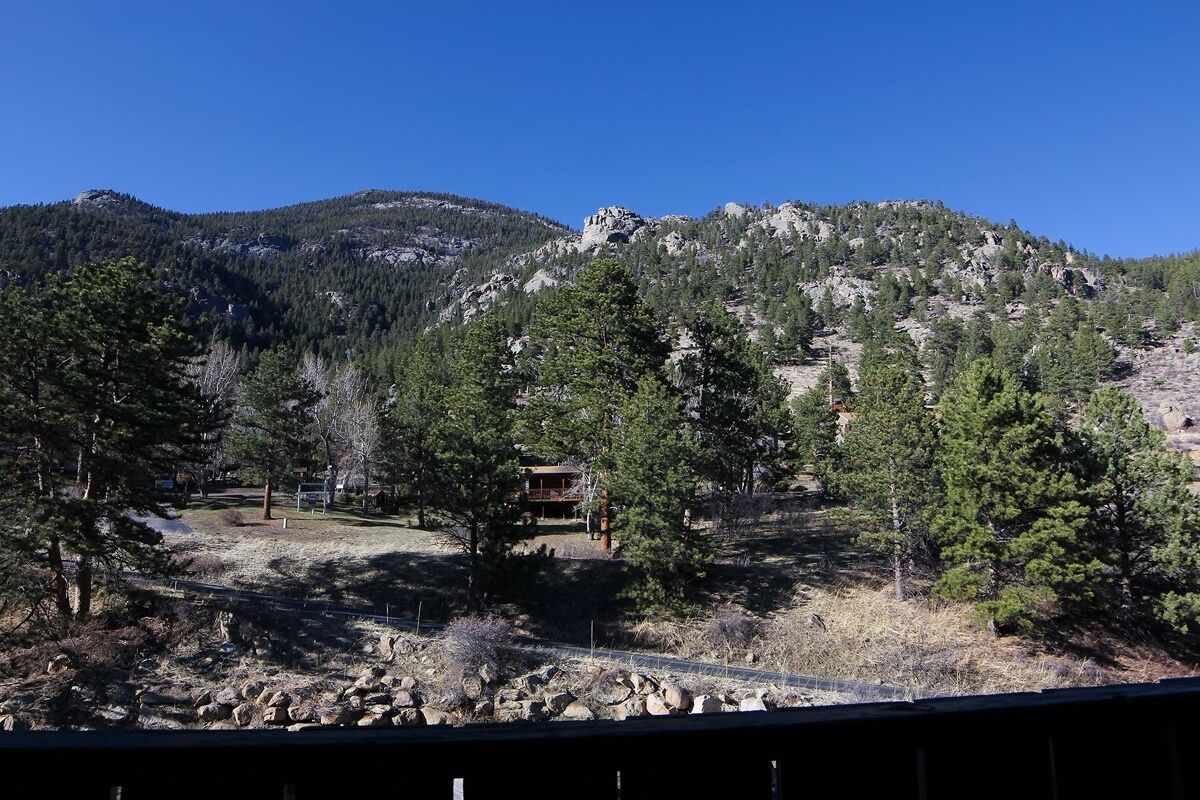A mountainous landscape with a cabin surrounded by trees.