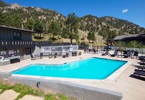 Una piscina con sillas de descanso y una torre de salvavidas, rodeada por un paisaje montañoso.