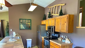 A compact kitchen with wooden cabinets, a refrigerator, a microwave, and a stove. - Lazy R Cottages: 15 2 Bedroom Cabin (Estes Park)