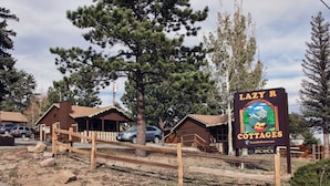 A sign for Lazy R Cottages with a rustic wooden cabin design, a wooden fence, and a clear sky. - Lazy R Cottages: 15 2 Bedroom Cabin (Estes Park)