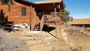 A log cabin with a porch, a staircase, and a picnic table. - Lazy R Cottages: 15 2 Bedroom Cabin (Estes Park)
