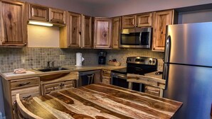 Una cocina con armarios de madera, un refrigerador de acero inoxidable, un microondas y una encimera de madera.