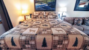 Ein Schlafzimmer mit einem großen Bett, einem Nachttisch, einer Lampe, einer Couch und einem gerahmten Bild an der Wand.