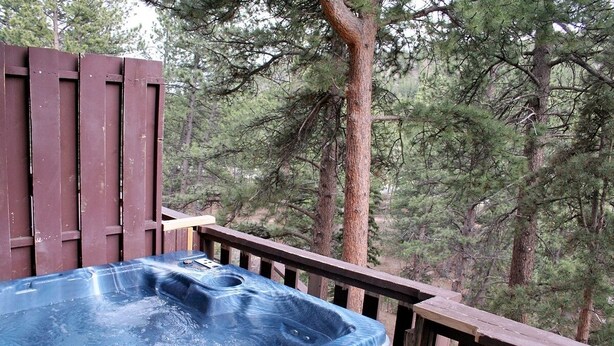 A hot tub on a wooden deck surrounded by trees. - Fawn Valley Inn: 296 1 Bedroom Apts (Estes Park)