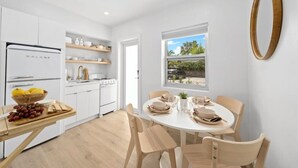 Eine moderne Küche mit weißen Schränken, einem Galanz-Kühlschrank und einem Essbereich mit rundem Tisch und Stühlen.