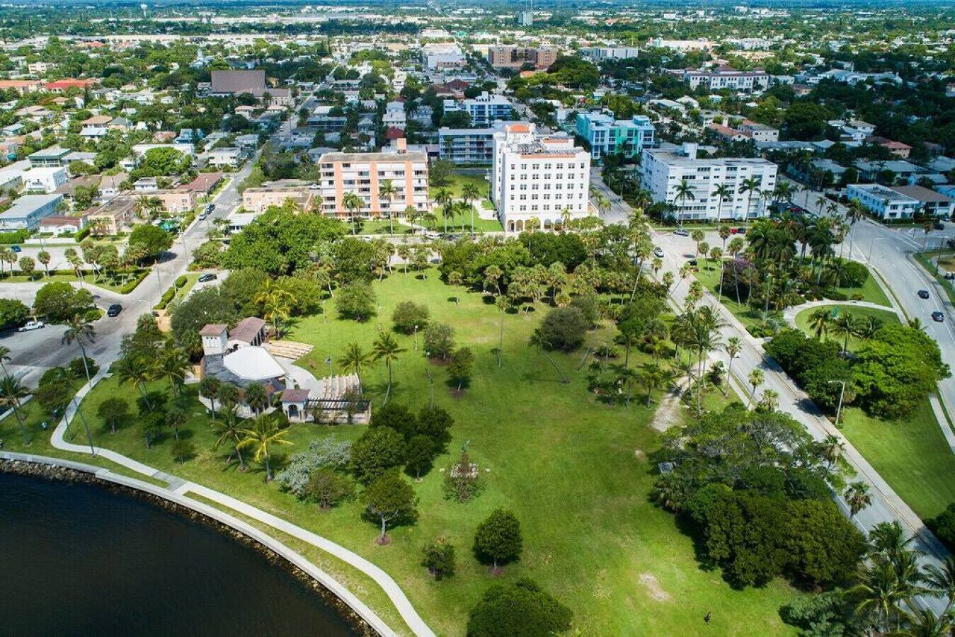 Vista aérea de una zona residencial con un gran parque cubierto de césped, varios edificios y una masa de agua.