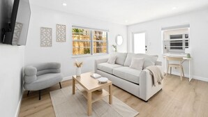 A modern living room with a grey sofa, a white sofa, a wooden coffee table, and a small desk with a chair.