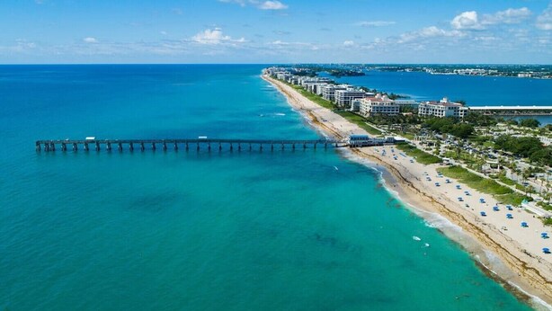 A coastal hotel with a pier extending into the sea, beachfront rooms, and a sandy beach with umbrellas. - Cute Retro Studio King Bed & Workspace - Villa 10 (Lake Worth)