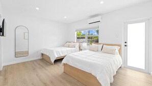 A modern bedroom with two beds, a large mirror, and a window with a view of greenery. - New 2 double beds -Near Golf & Beach - Villa 8 (Lake Worth)