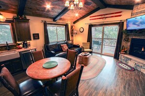 A cozy living room with a fireplace, a dining area with a round table, and a kitchen with a stone countertop. - Fawn Valley Inn: 269 1 Bedroom Condo (Estes Park)