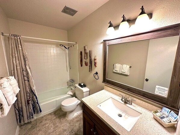 A bathroom with a bathtub, toilet, sink, and a large mirror.