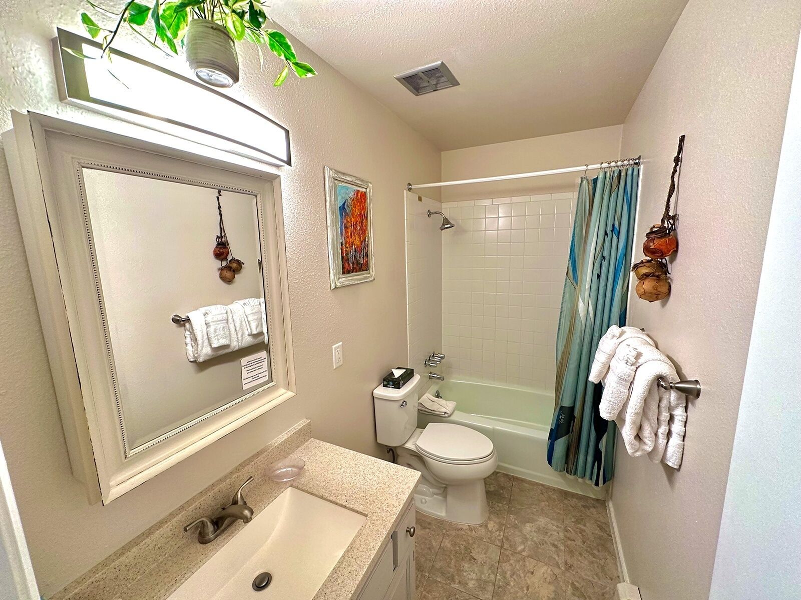 A bathroom with a sink, toilet, and shower. There is a mirror above the sink, and a towel rack with towels.