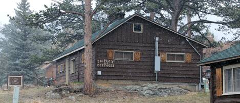 Un edificio rustico in legno con l'insegna “TRIPLE R COTTAGES”, dall'aspetto semplice e con un tetto spiovente.
