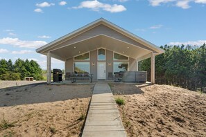 A modern house with a covered patio, a pathway leading to the entrance, and a barbecue area.