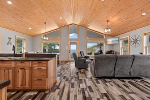 A spacious kitchen with wooden cabinets, a large island, and a dining area with a gray sofa.