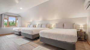 Ein Schlafzimmer mit drei Betten, einem großen Fenster und einem Deckenventilator.