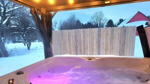 Ein Whirlpool mit einer Holzterrasse und einem Holzzaun im Hintergrund.