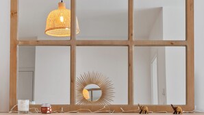 A room with a large arched mirror, a hanging pendant light, and a decorative sunburst mirror on the wall. - Stylish Apt Bouneweg-Süd Book Now ID225 (Luxembourg City)