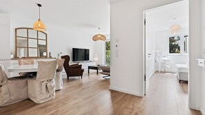 A modern living room with a TV, beige chairs, a wooden coffee table, and a large mirror. - Stylish Apt Bouneweg-Süd Book Now ID225 (Luxembourg City)