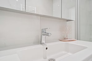 A modern bathroom with a white sink, chrome faucet, and a glass shower enclosure. - Stylish Apt Bouneweg-Süd Book Now ID225 (Luxembourg City)