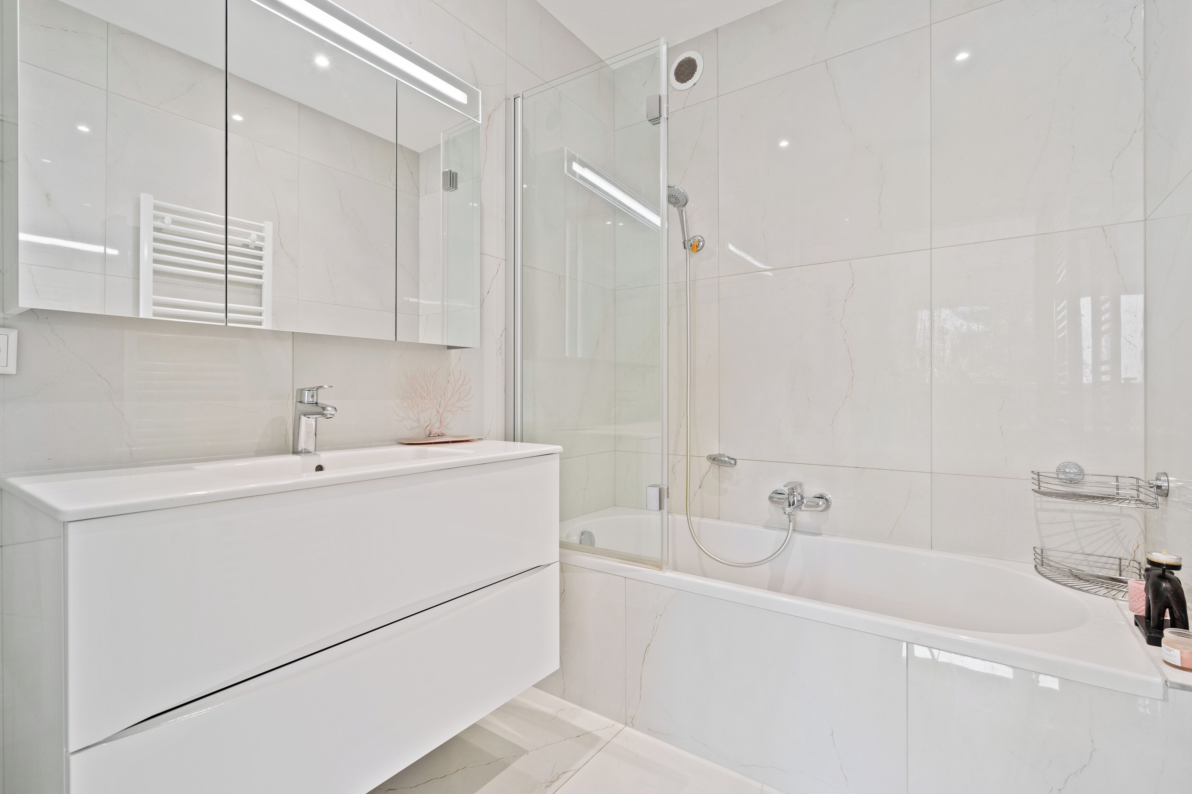 A modern bathroom with a glass-enclosed shower, a white vanity with a mirror, and a bathtub.