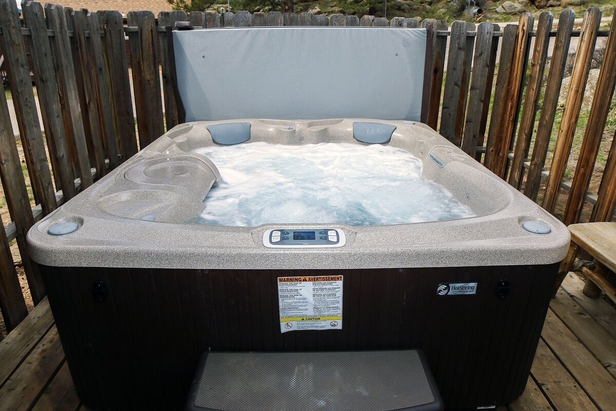 Ein Whirlpool mit Bedienfeld, umgeben von einer Holzterrasse und einem Holzzaun.