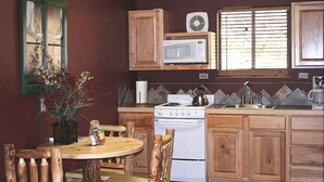 A kitchen with wooden cabinets, a white stove, a microwave, and a window with blinds.