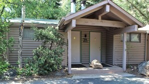 A cabin with a front porch, two doors, and a chimney.