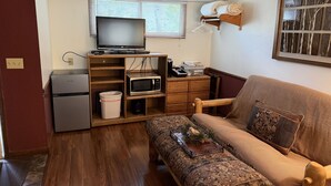 A compact living space with a sofa, a television, a microwave, and a small refrigerator.