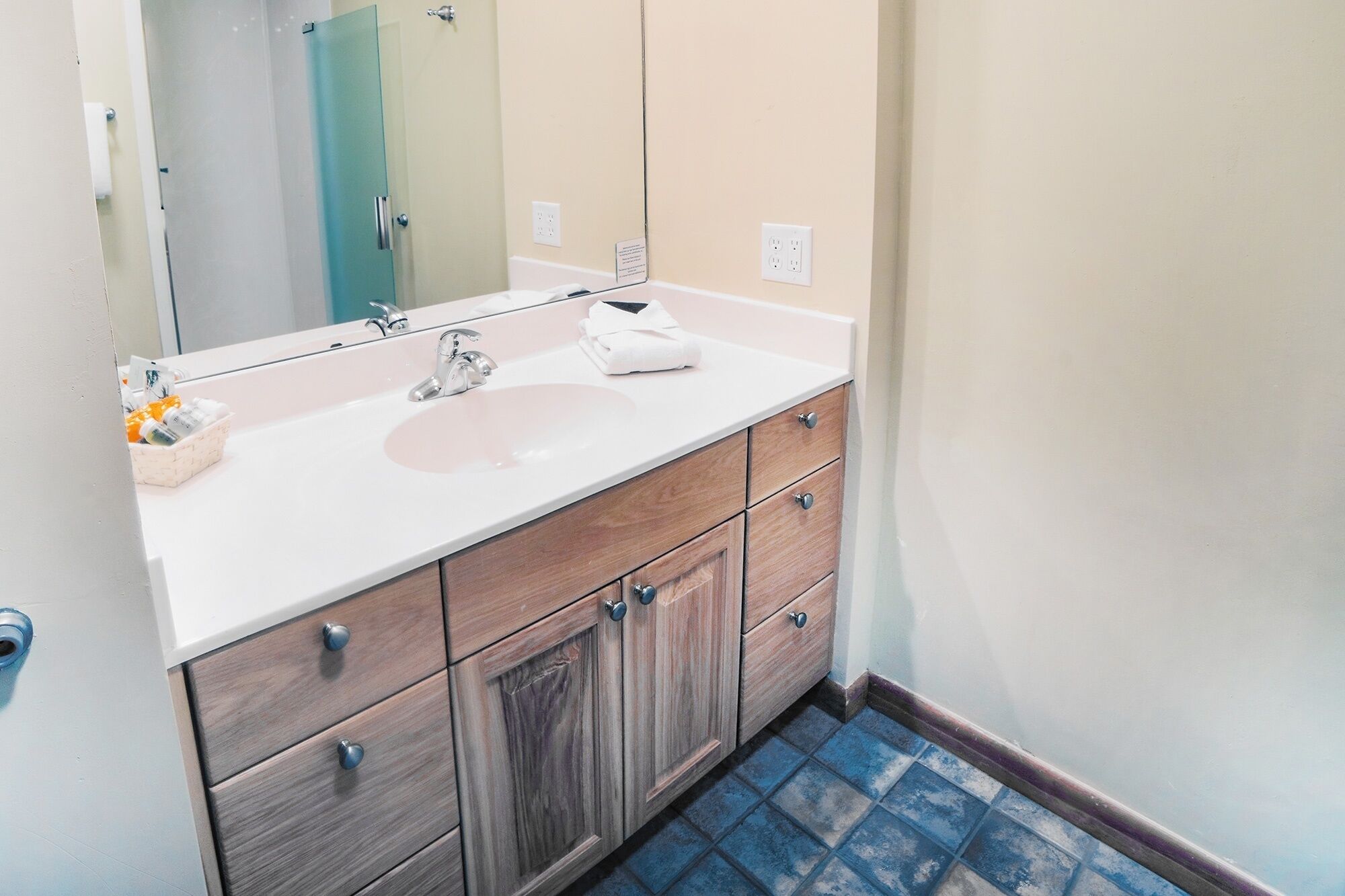 A bathroom with a white sink, wooden vanity, and a large mirror.