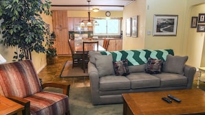 A living room with a grey sofa, a wooden coffee table, and a striped armchair. - Fawn Valley Inn: 240 2 Bedroom Condo (Estes Park)