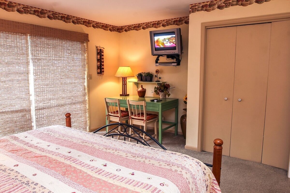 A bedroom with a bed, a desk, a chair, a television, and a wardrobe.